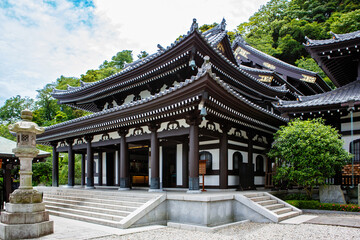 Fototapeta premium Traditional Buddhist temple in Kamakura, Japan, with ornate wooden architecture and visitors on the steps.