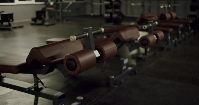 Empty fitness club with a row of professional hyperextension benches ready for a workout. Athletic, bodybuilding, and fitness concept with no people in a modern gym training facility