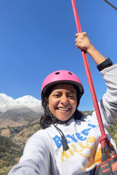 Happy girl ziplining in mountain valley landscape. UGC