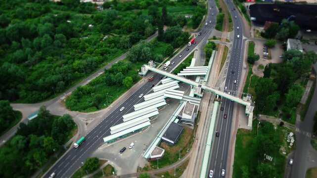 Aerial view of a wide highway with flowing cars and trucks, guardrails, and a pedestrian overpass spanning the road, modern transport infrastructure. 4k footage