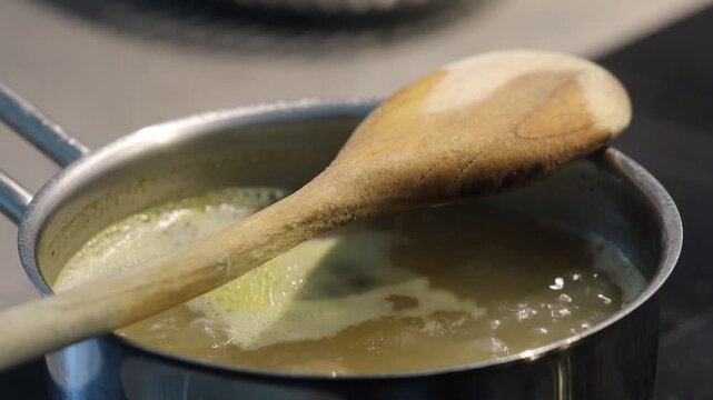 Stockholm, Sweden Water mixed with bouillon boils on a stovetop with a wooden spoon to prevent overflow. 