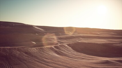 Obraz premium Golden dunes rise and fall as the sun casts long shadows across the tranquil desert landscape. A serene atmosphere envelops the arid terrain, showcasing natures beauty.