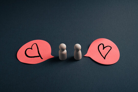 Mutual love concept with wooden figures and heart speech bubbles symbolizing emotional reciprocity