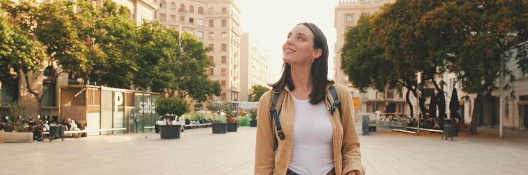 Traveler girl, with backpack on her shoulders, walks in the historical part of European city. Panoramic