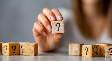 Woman is holding a wooden block with a question mark on it, surrounded by other wooden blocks with question marks on t