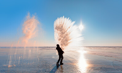 Man throwing boiling hot water freezing mid air.  Water condensate freezes and forms ice crystals -...