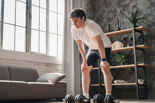 Dumbbells, resting and strong man in fitness training, exercise or home workout for wellness, lifting or balance. Development, challenge or male athlete with weights for muscle, power or body growth