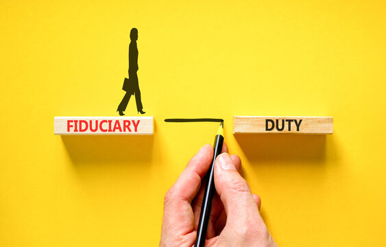 Fiduciary duty words symbol. Concept words Fiduciary duty on beautiful wooden blocks. Beautiful yellow background. Businessman hand. Business and Fiduciary duty words concept. Copy space.