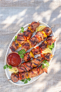 Delicious grilled kebabs with peppers and lemon slices served on a platter with sauce
