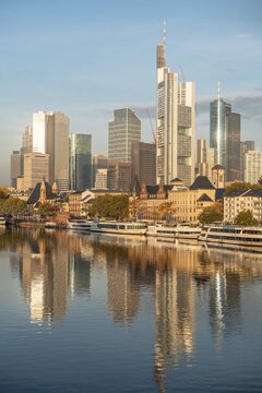 Excursion boats on the river bank, view over the Main, skyline reflected in the river, skyscrapers in the banking district in the morning light, Frankfurt am Main, Hesse, Germany