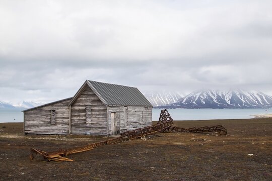 Former mining station Calypsobyen, wooden barrack and dilapidated metal mast, view of Bellsund, Spitsbergen Island, Norway