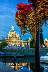 Fototapeta premium Victoria Parliament Building Inner Harbour Morning and Flower. Flower basket over Victoria's Inner Harbor and marina in downtown Victoria. The historic Legislative Building in the background. 