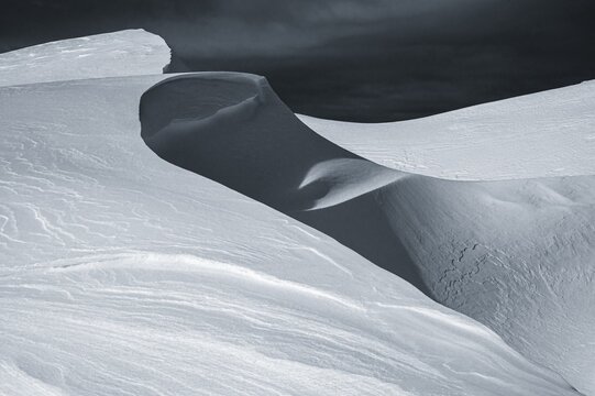 Snow cornice against a dark sky at the summit of Toreck, Riezlern, Kleinwalsertal, Vorarlberg, Austria