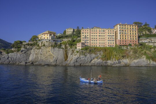 Historic skyscrapers and fishing boat leaving the port of, Camogli, Genoa, Italy