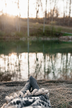 A woman's feet relaxing by a pond at sunrise.