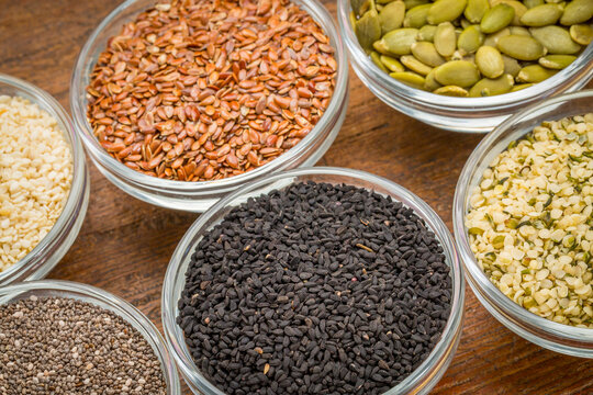 black cumin seeds (Nigella sativa) in a small bowl against rustic barn wood with chia and other healthy seed