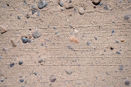 Textura de suelo con arena compacta piedras y marcas de huellas