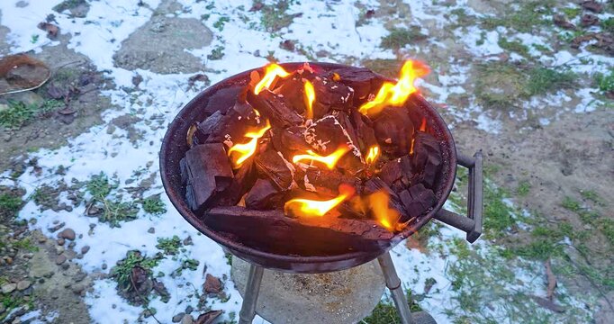 A fire in a barbecue grill in a winter courtyard