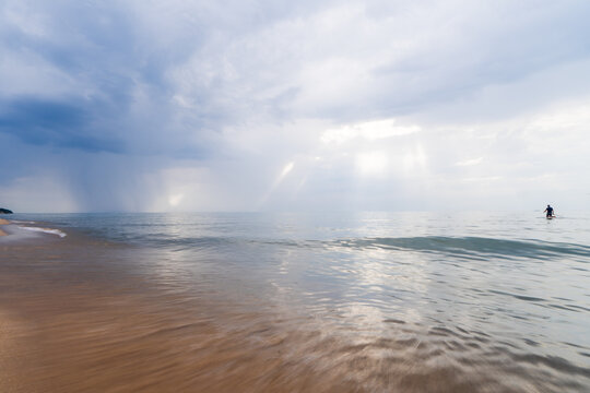 Paddleboarder on Lake Michigan under dramatic storm clouds on horizon