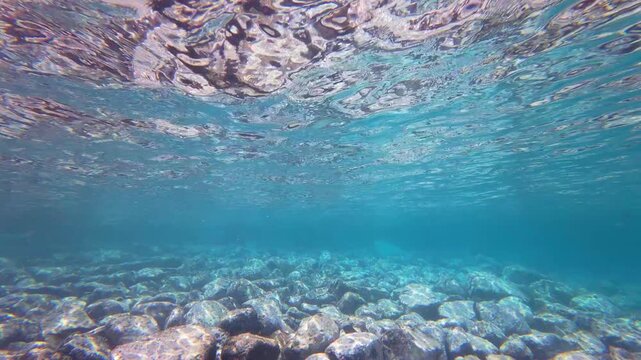 Sunlight refracting through clear water onto a seabed of smooth volcanic rocks and stones on Pr&iacute;ncipe Island, S&atilde;o Tom&eacute; and Pr&iacute;ncipe.