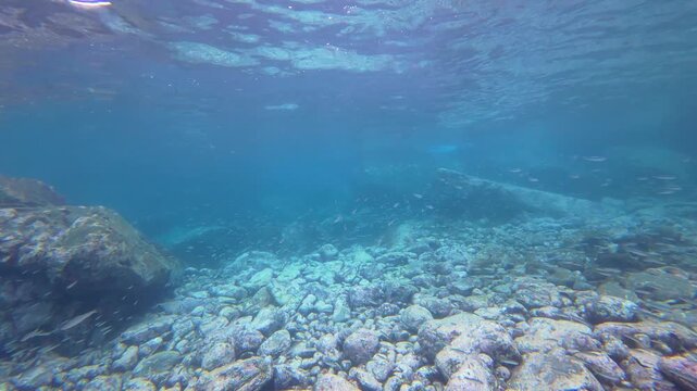 Sunlight refracting through clear water onto a seabed of smooth volcanic rocks and stones on Pr&iacute;ncipe Island, S&atilde;o Tom&eacute; and Pr&iacute;ncipe.