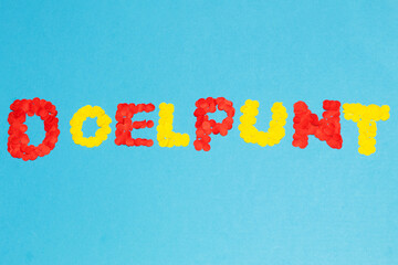 Dutch word “goal” formed with red and yellow confetti on a blue background, concept of a goal in soccer © Andres Serna