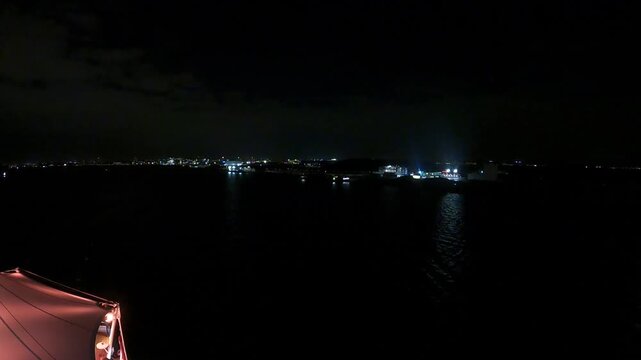 Nachtaufnahme vom Schiff &uuml;ber dunkles Meer mit Lichtern in der Ferne, ruhige maritime Stimmung, Reise und Schifffahrt bei Nacht mit Copyspace