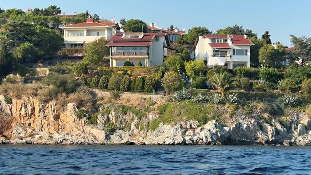 Hillside villas with red-tiled roofs rising above rocky coastal cliffs on Sedef Island, Istanbul