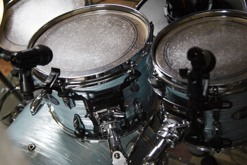 Drum set with microphones placed on the toms in a music studio during a recording session in the evening