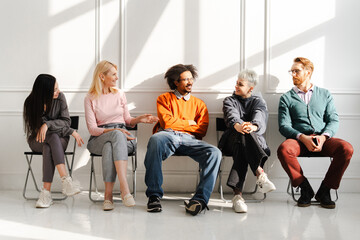 Fototapeta premium Group of diverse, multinational colleagues sitting on chairs talking each other