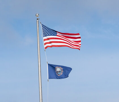 New Hampshire state flag and USA flag waving on the pole in the wind