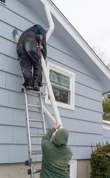 manual worker installing radon mitigation system outside the house