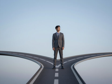 Young Asian Businessman In Grey Suit Standing At Highway Fork Choosing Direction