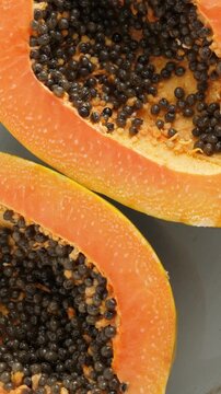 Top view of ripe half cut papaya. Rotating. Vertical footage