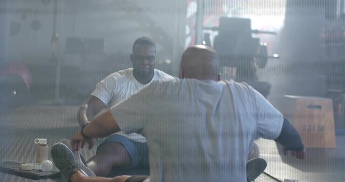 Scanlines clearing, revealing two men performing partner situps on gym mats for core fitness
