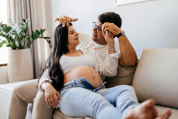 Obraz premium Pregnant woman relaxing with partner on sofa