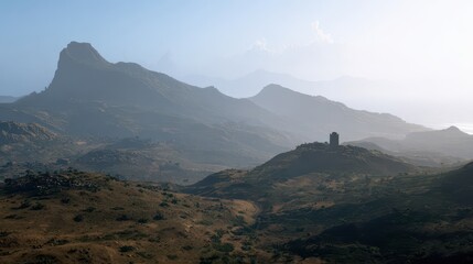 Obraz premium A vast, mountain landscape, bathed in soft light, showcases a solitary ancient tower perched atop a hill, with rolling hills and distant peaks shrouded in a hazy atmosphere.