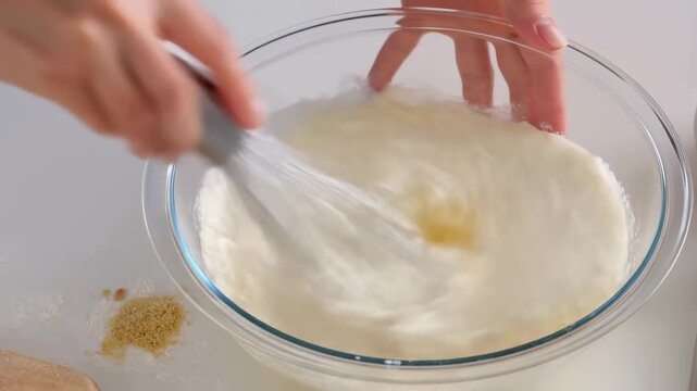 Mixing ingredients in a glass bowl with a whisk. Preparing a delicious batter for baking or cooking