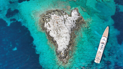 Fototapeta premium Aerial drone photo of luxury yacht anchored in paradise heart shaped island bay with turquoise crystal clear sea