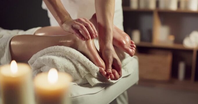 Woman therapist performs soothing foot massage at spa. Warm candles and towels set a calm scene for wellness and relaxation marketing, spa menus, and ads. Calm spa foot reflexology concept.