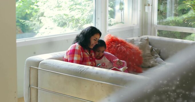 Mother guiding child's finger after child pointing at book on sofa, teaching reading for education