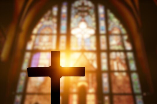Silhouette of wooden cross inside antique church