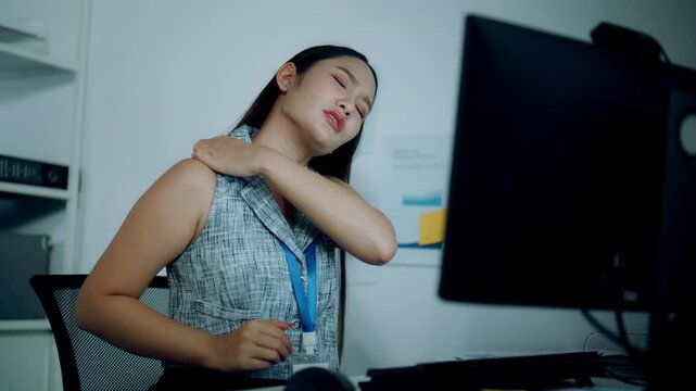 Businesswoman suffering neck and shoulder pain while working at computer in office, highlighting poor posture and office syndrome.