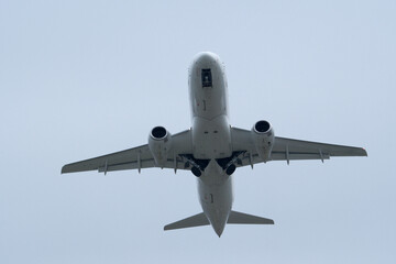 White passenger plane flying in cloudy sky. White aircraft against cloudy background, aviation travel