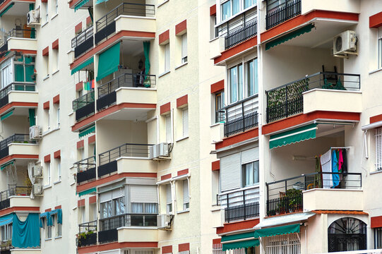 Residential apartment building with balconies, green awnings and everyday domestic details such as laundry and air conditioning units in M&oacute;stoles, Madrid, Spain.
