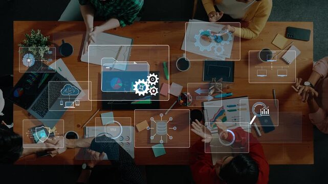 A dynamic meeting scene showcasing a diverse group of professionals collaborating over data and technology, surrounded by charts and digital devices on a wooden table. Raster