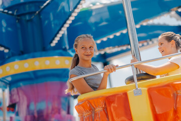 Two girls having fun on a spinning ride at amusement park © Ljustina