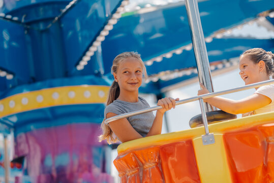 Two girls having fun on a spinning ride at amusement park