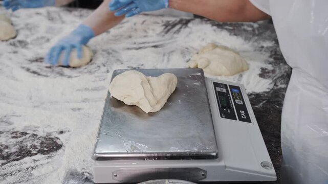 Professional baker weighing dough portions on a digital scale in a commercial bakery