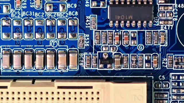 Densely packed SMD capacitors, resistors and edge connector fill a blue PCB in extreme macro close-up under studio lighting